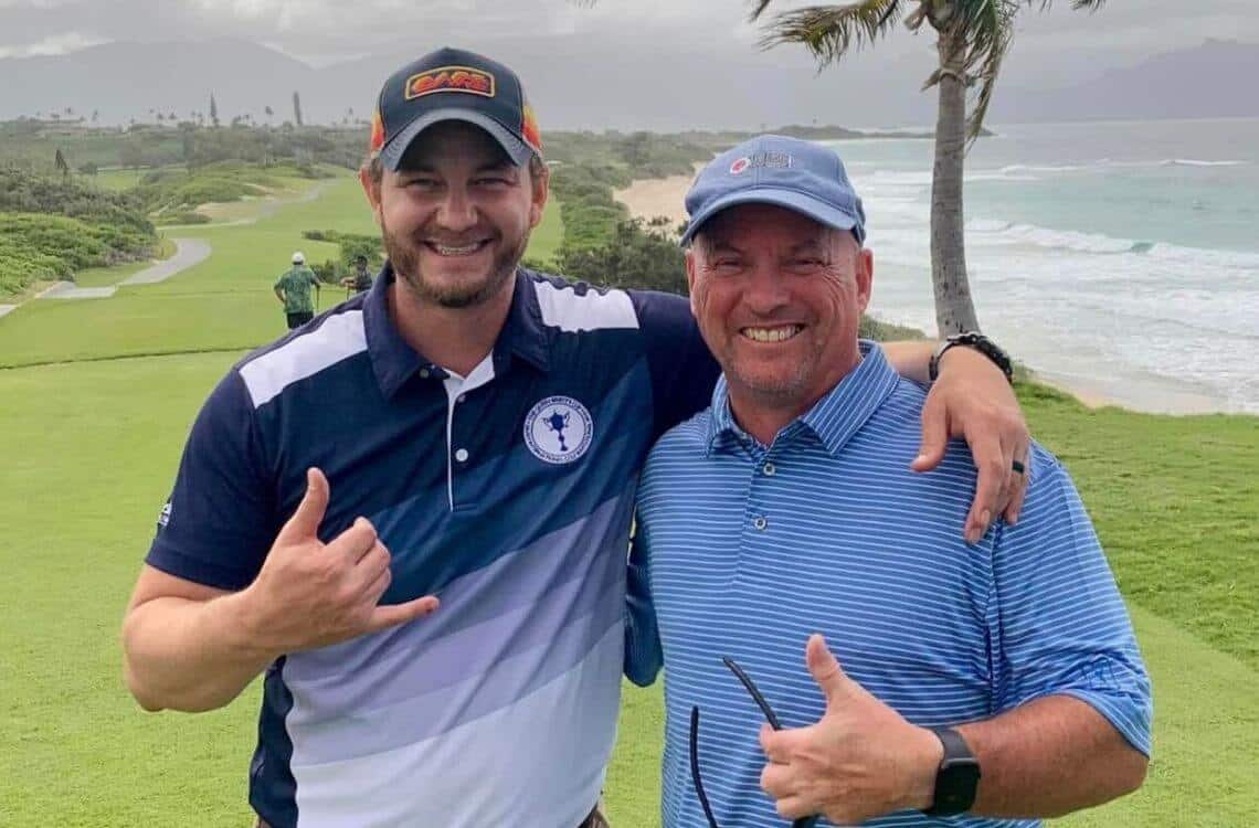 Two TST employees taking a photo on a golf course by the beach