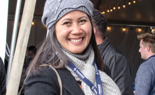 TST employee smiling at an event wearing a winter hat