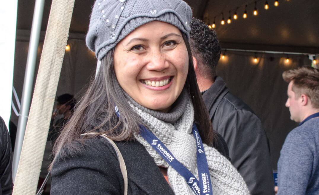 TST employee smiling at an event wearing a winter hat